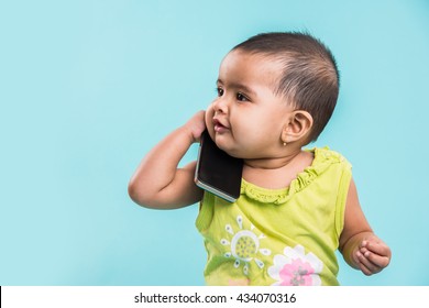 Cute little Indian/asian infant baby girl  using smartphone and calling mother while sitting isolated over white background