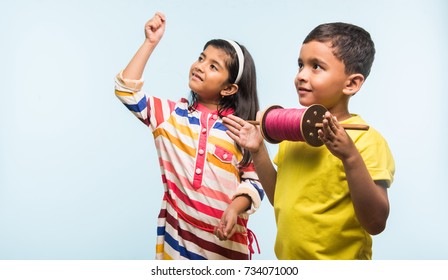 Cute Little Indian/asian Kids Flying Kite On Makar Sankranti Or Uttarayan Festival, Against Sky Blue Background