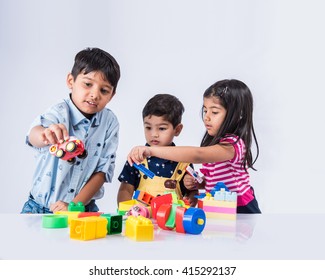 Cute little Indian/asian kids playing with toys or blocks and having fun while sitting at table or isolated over white background