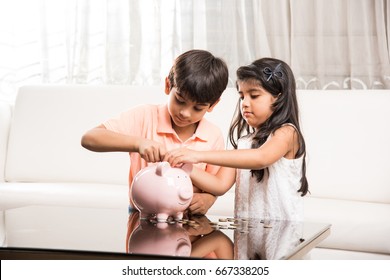 Cute Little Indian/asian Kids Saving Coins In Piggy Bank At Home