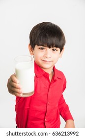 Cute little Indian/Asian playful boy holding or drinking a glass full of Milk, isolated over  white background