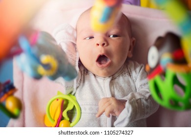 Cute little infant baby newborn playing with toys on colorful ma