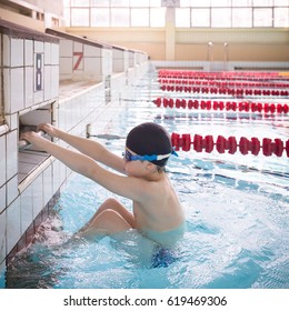 Cute Little Kid Boy Is Ready For Swimming Competition  In The Sport Swimming Pool. Child Ready To Jump And Swimming Race. Training For Competition. Sport Activities For Children Indoors.