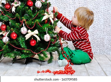 Cute Little Kid Decorating Christmas Tree With Red Beads