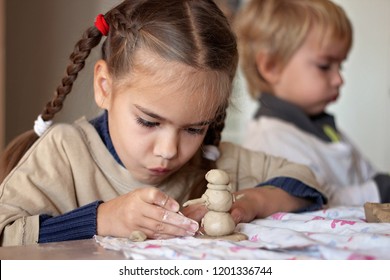 Cute little kid playing with modeling clay in pottery workshop, craft and clay art, child creative activities, education in Arts - Powered by Shutterstock