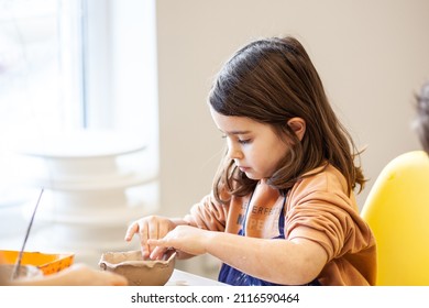 Cute little kid playing with modeling clay in pottery workshop, craft and clay art, child creative activities, education in Arts - Shutterstock ID 2116590464