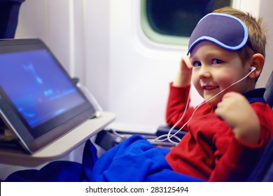 Cute Little Kid Watching Cartoons During The Long Flight In Airplane