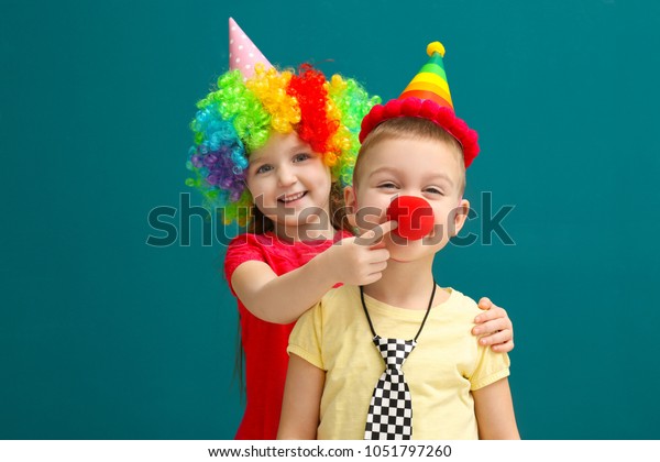 Cute little kids in funny disguise on color background. April fool's day celebration