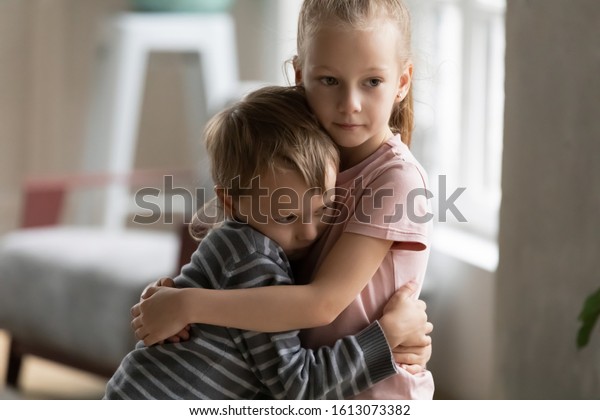 Cute little kids siblings hug and cuddle at home\
show love and care, small girl sister embrace hurt upset\
preschooler brother, take care of cousin, family relationships,\
children support concept