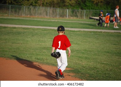 Cute Little League Baseball Player Walking On Field From Behind.