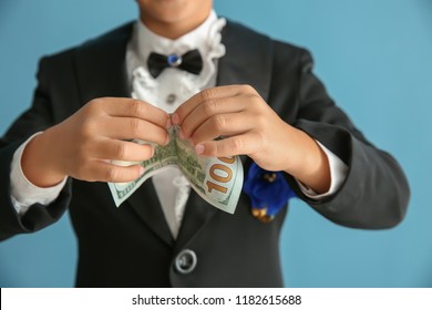 Cute Little Magician Showing Trick With Money On Color Background, Closeup