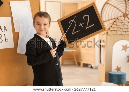Cute little Math teacher with pointer and chalkboard at home