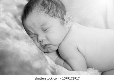 Cute little newborn baby curled up sleeping on a blanket. Mono tone - Shutterstock ID 1079172917