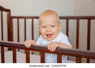 Cute little newborn baby is sitting in a crib. the baby boy is sitting in the crib smiling. The concept of childhood