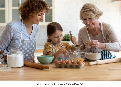 Cute little preschool kid girl learning preparing homemade pastry with affectionate young mother and caring middle aged retired granny in modern kitchen, cooking weekend family activity concept. - Powered by Shutterstock