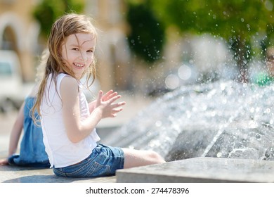 Cute Little Preschooler Girl Playing With A City Fountain On Hot And Sunny Summer Day