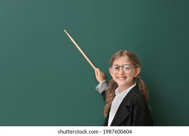 Cute little schoolgirl with pointer near blackboard in classroom - Powered by Shutterstock