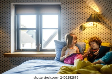 Cute little siblings in bed using tablet at home - Powered by Shutterstock