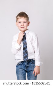 Cute little smiling boy in white shirt and in a stylish tie posing on a light-gray background. Portrait of fashionable male child, gray wall on background. Concept of children style and fashion