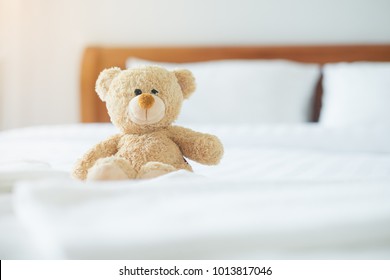 Cute little teddy bear sitting alone on white bed in morning. - Powered by Shutterstock