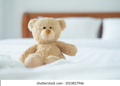 Cute little teddy bear sitting alone on white bed in morning. - Powered by Shutterstock