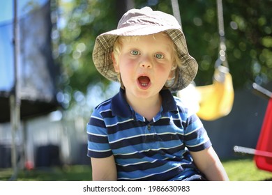 Cute Little Toddler Boy Making Surprised Face Wearing Sun Hat Playing In Backyard At Home