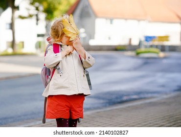Cute little toddler girl on her first day going to playschool. Healthy happy child walking to nursery school. Kid with backpack going to day care on the city street, outdoors