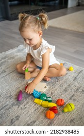 Cute Little Toddler Girl Playing At Home With Eco Wooden Toys. Happy Healthy Excited Child Cutting Vegetables And Fruits With Toy Knife. The Child Playing Educational Games. High Quality Photo