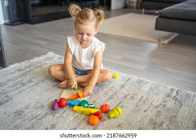 Cute Little Toddler Girl Playing At Home With Eco Wooden Toys. Happy Healthy Excited Child Cutting Vegetables And Fruits With Toy Knife. The Child Playing Educational Games. High Quality Photo