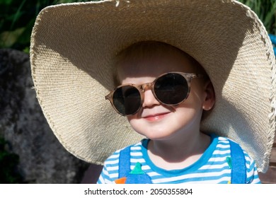 Cute Little Toddler Wearing An Oversized Sun Hat And Sunglasses Relaxing In The Sun