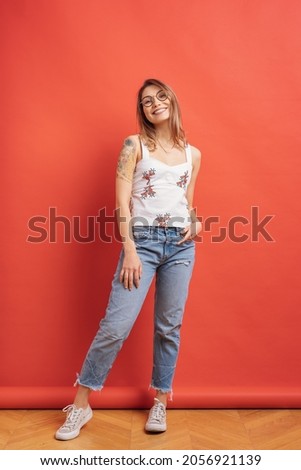 Cute long-haired female model posing with a smiling face expression on red background