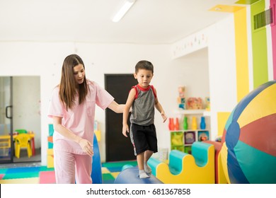 Cute Looking Boy Walking On A Beam To Practice His Balance With The Help Of A Children Physical Therapist