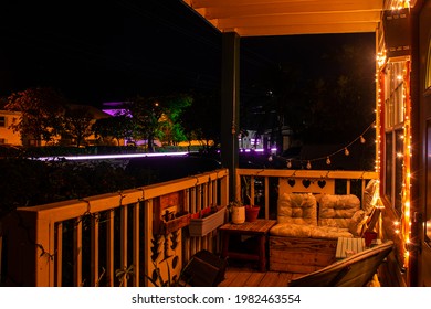 A Cute Looking Shot Of A Porch In Front Of Someone's House Taken At Night With A Slow Exposure That Catches The Lights Of A Passing Car At The Same Time