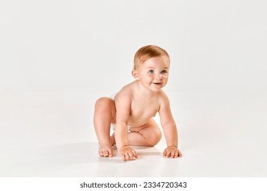 Cute, lovely little baby girl, toddler in diaper sitting on floor and starting crawling against white studio background. Concept of childhood, newborn lifestyle, happiness, care. Copy space for ad - Powered by Shutterstock