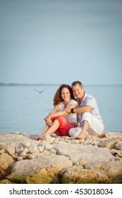 Cute Middle Aged Couple Sitting On Rocks At The Beach Portrait