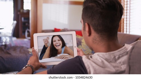 Cute millennial couple video chatting or having a facetime conversation with his girlfriend on tablet computer