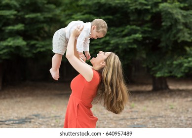 A Cute Millennial Mother Lifting Her Two Year Old Toddler Above Her Head