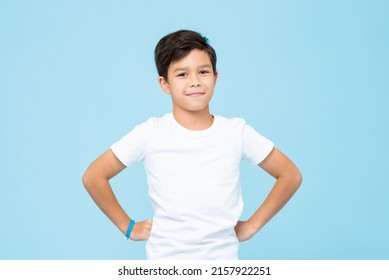 Cute mixed race boy smiling with arms akimbo in studio isolated light blue color background