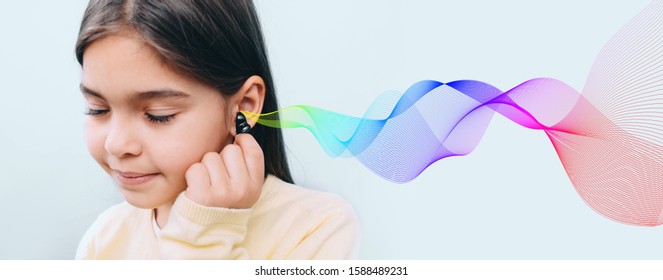 Cute Mixed Race Child Holding Hearing Aid Near Her Ear. Colored Sound Waves Showing Variety Of Sounds Going To The Ear. It's Great To Hear