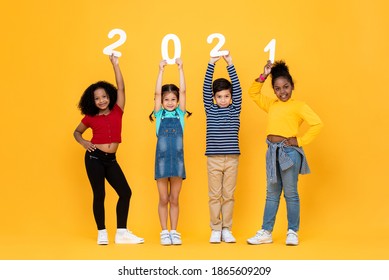 Cute Mixed Race Kids Smiling And Holding 2021 Numbers Isolated On Yellow Background For New Year Concepts