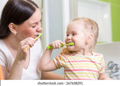 Cute Mom Teaching Kid Teeth Brushing In Bathroom