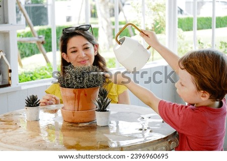 Cute mother and baby watering plants happy family.