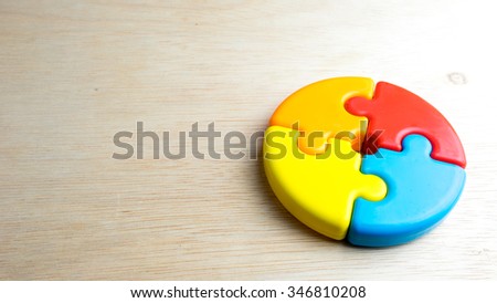 Cute and multicolor plastic pie chart or puzzle on wooden surface. Concept of process solution and teamwork collaboration. Slightly de-focused and close-up shot. Copy space.