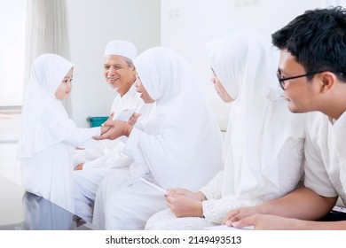 Cute Muslim Little Girl Getting Money Envelope From Her Family During Eid Mubarak In The Living Room. Shot At Home