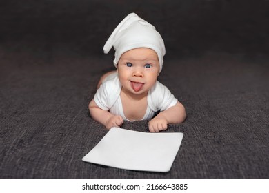 Cute Naughty Kid In A White Hat Stuck Out His Tongue And Holds A Sign With A Place For Text. Dark Gray Background.