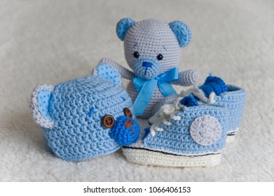 Cute Newborn Baby Boy Fashion Set Of Blue Booties, Teddy Beanie Hat And Stuffed Teddy Bear Toy Handmade With Crochet Technique From Natural Wool On A Fluffy Blanket