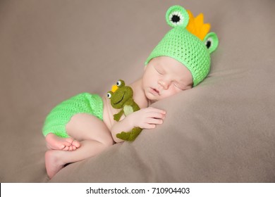 Cute Newborn Baby In A Frog Costume With Plush Toy Frog