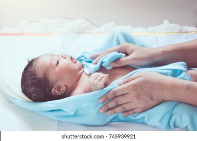 Cute newborn baby girl in towel after bath with mother hands rub her body dry with tenderness - Powered by Shutterstock