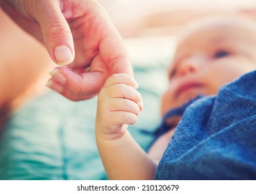 Cute newborn baby holding mother's hand