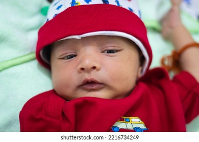 Cute Newborn Baby Looking At Camera In Red Dress From Different Angle